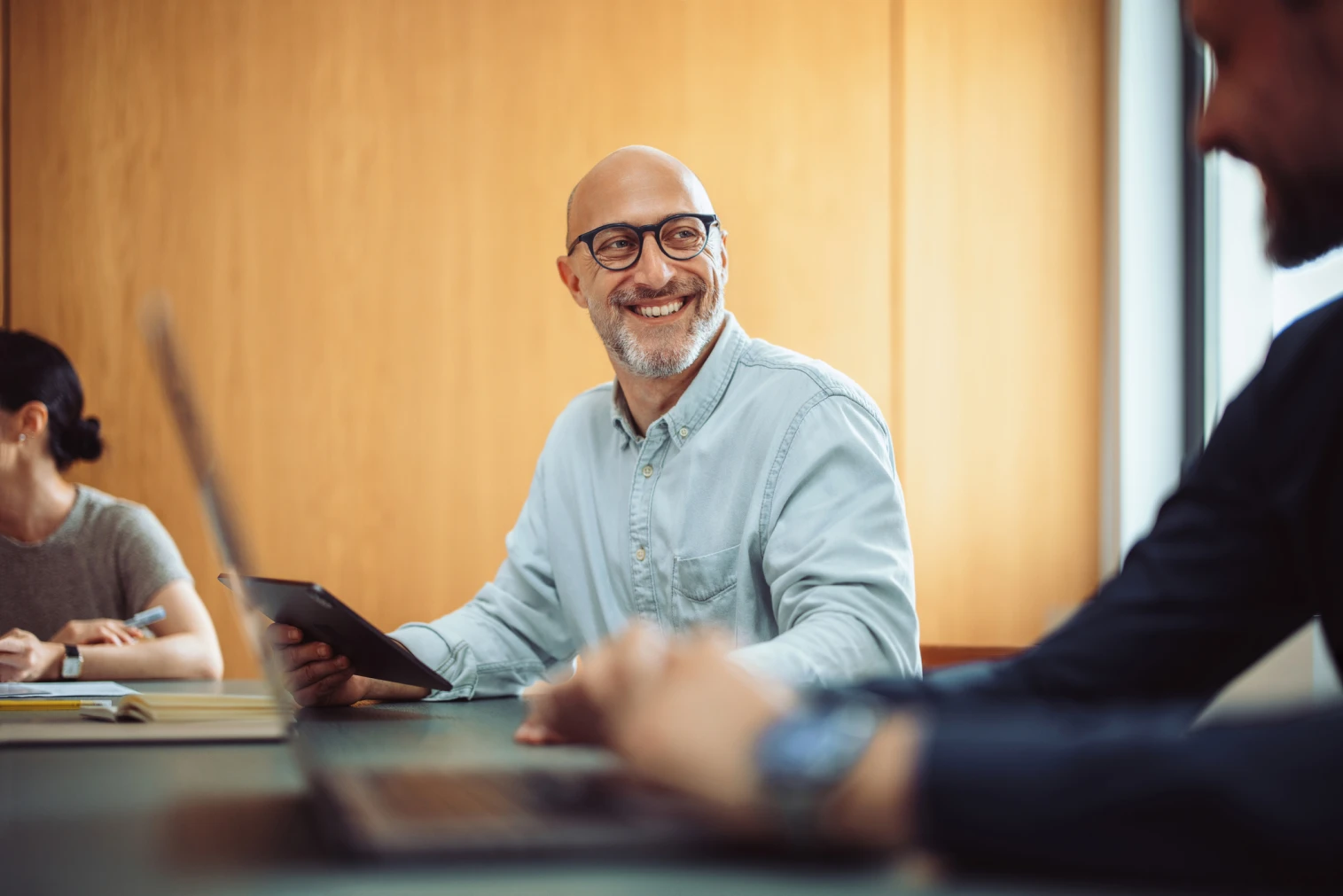 Man in meeting with laptop and tablets.