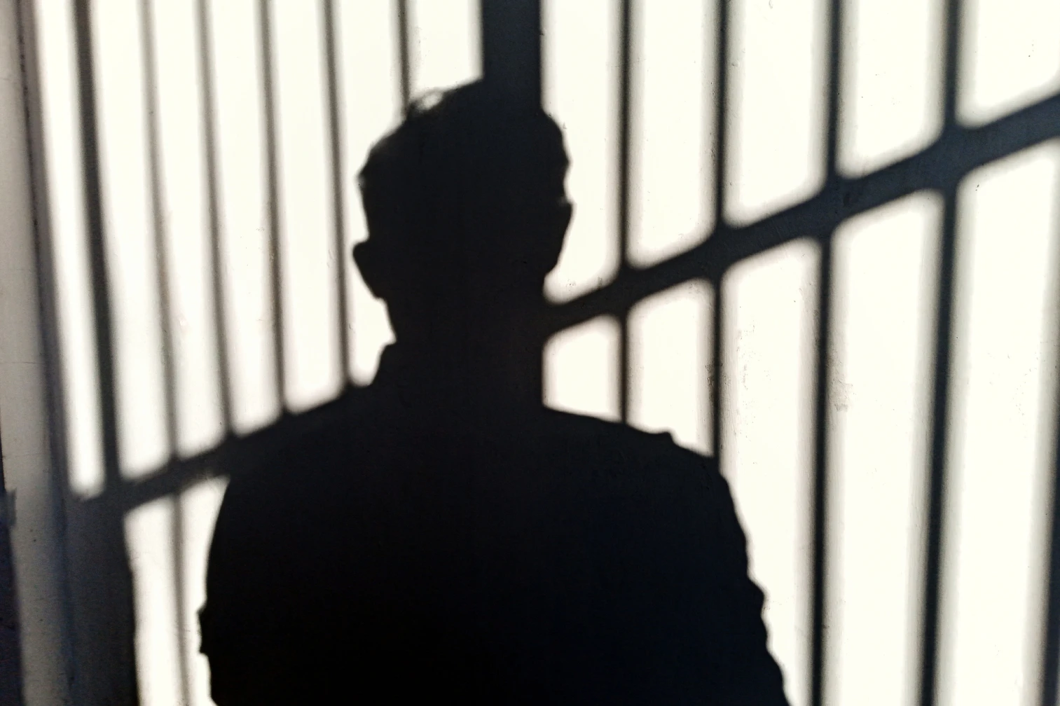 Shadow of a person behind bars